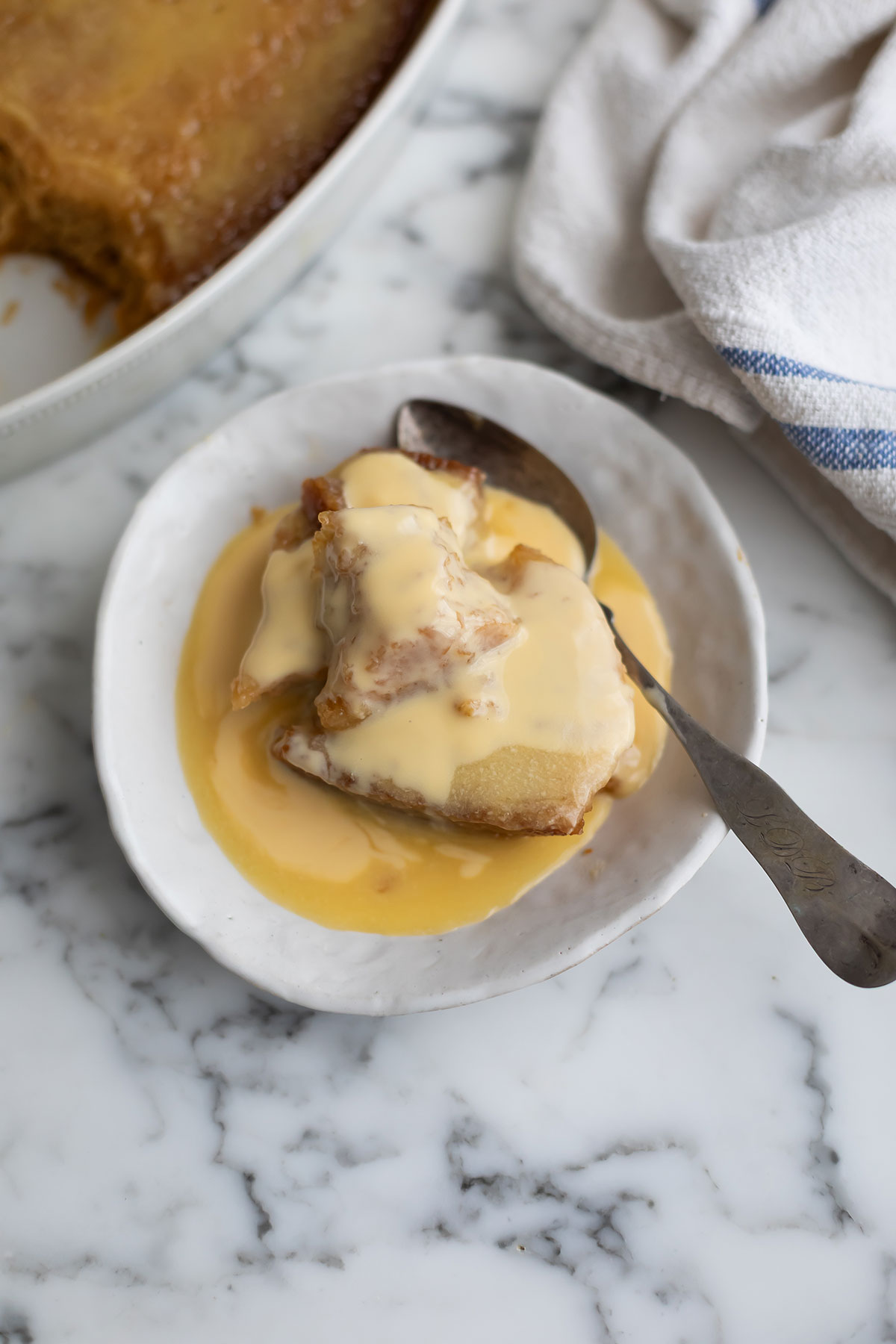 The best malva pudding recipe with orange • Drizzle and Dip Slice of malva pudding with custard on a white plate, generously drizzled with creamy vanilla custard.