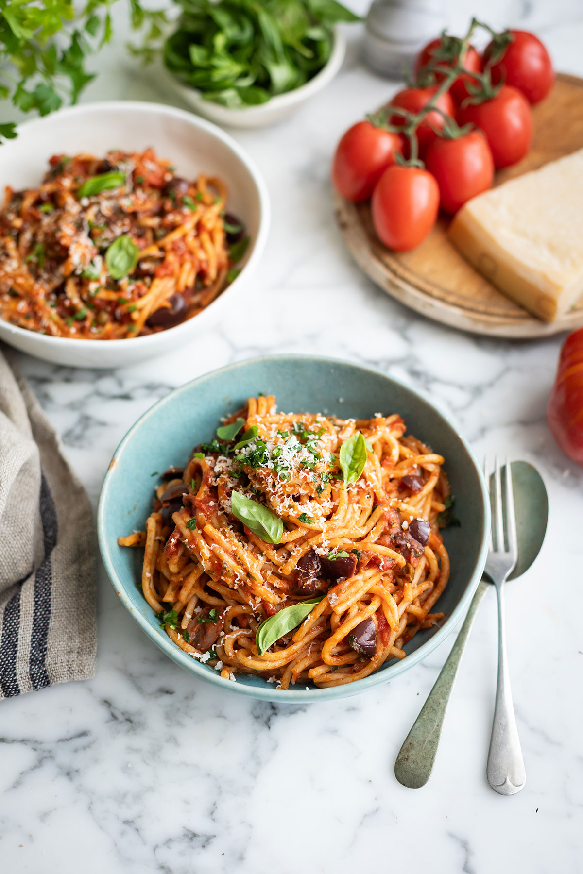 A bowl of spaghetti puttanesca on a. marble table