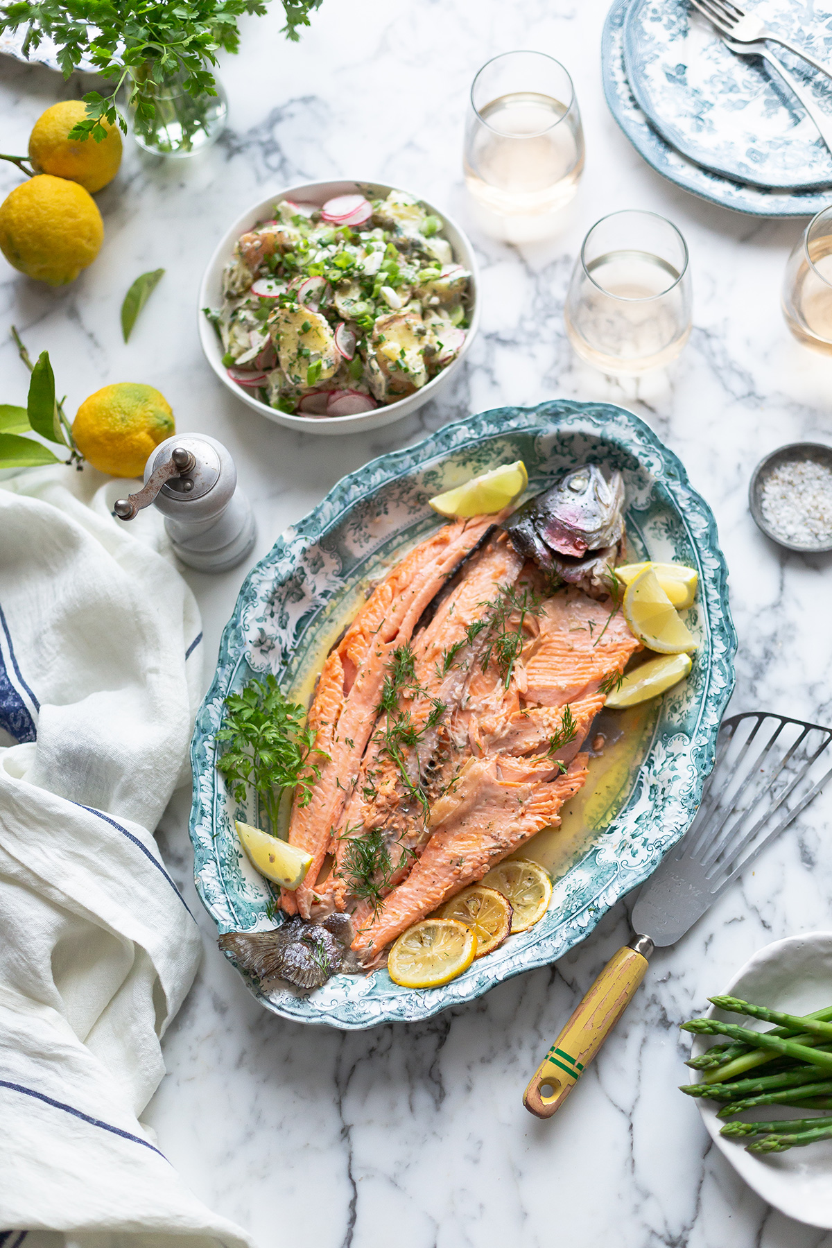 A platter of whole roasted trout with a new potato and herb salad