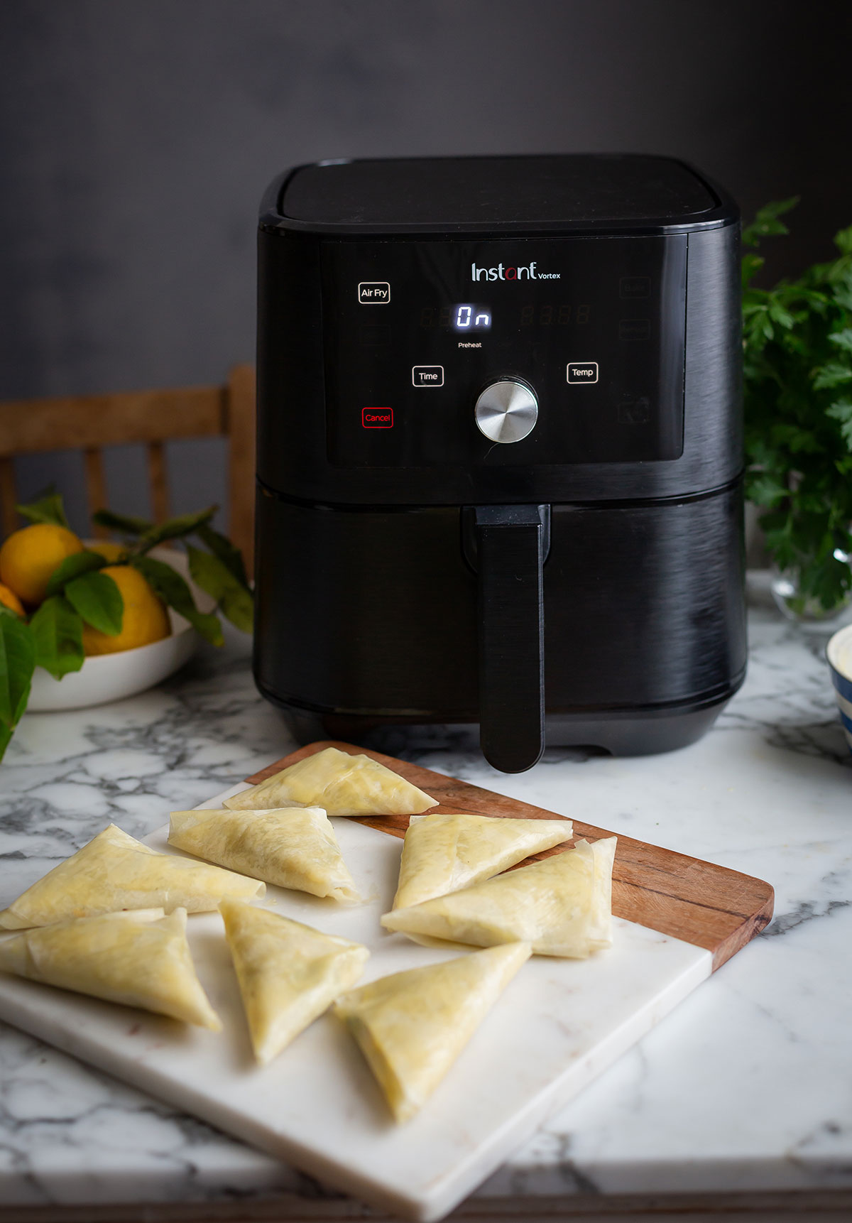 An Air fryer on a counter with unbaked zucchini and cheese phyllo pies recipe 