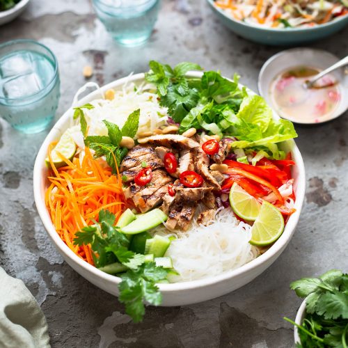 Vietnamese rice noodle salad with grilled chicken recipe in a bowl with garnishes and nuoc cham dressing.