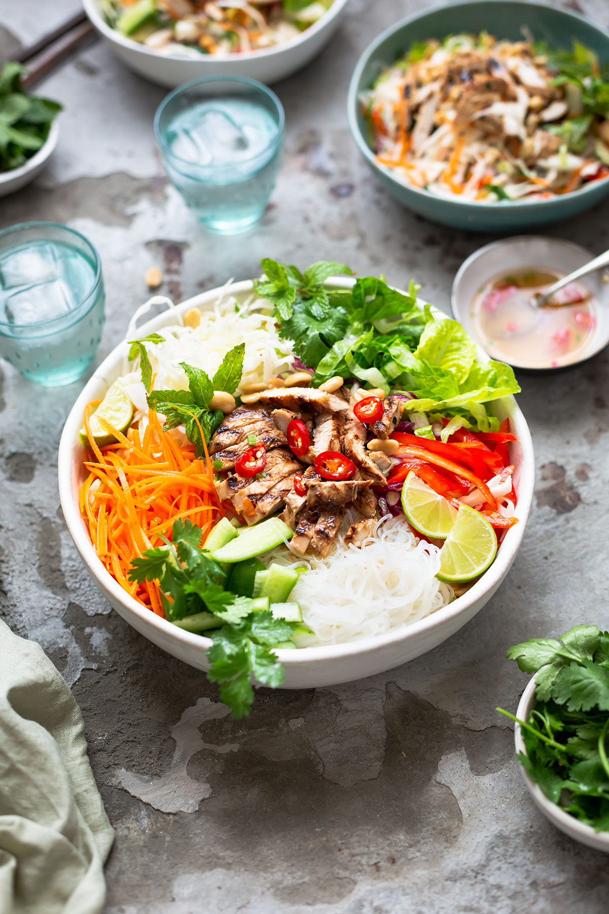Vietnamese rice noodle salad with grilled chicken recipe in a bowl with garnishes and nuoc cham dressing.
