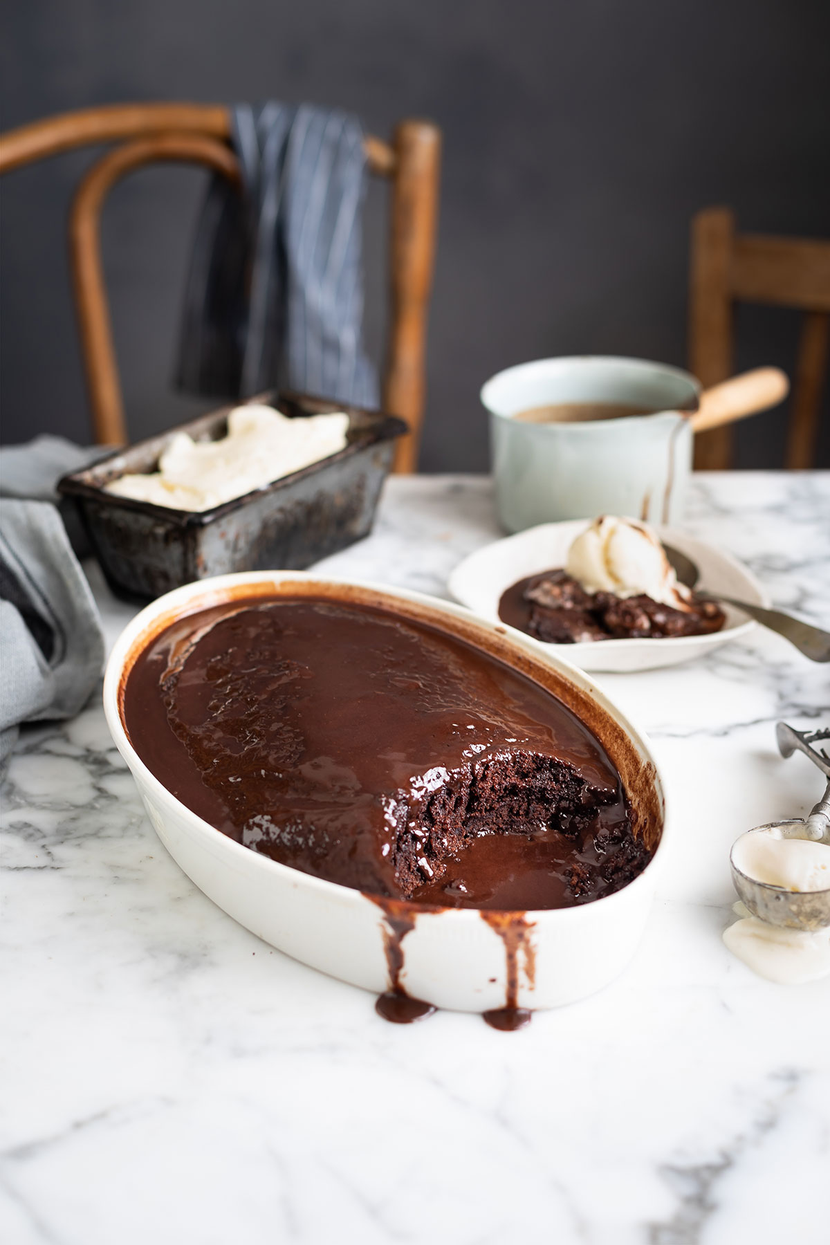 A baking dish with the best chocolate malva pudding and a portion scooped out