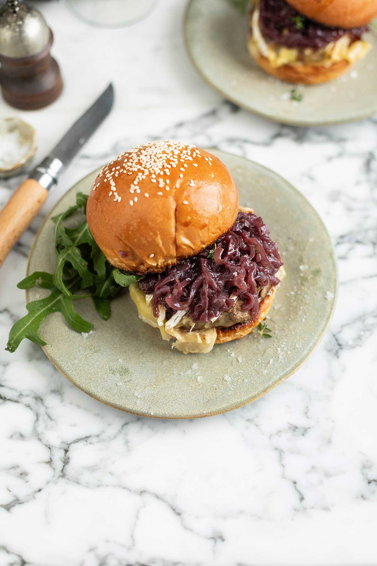 A Brie burger with onions caramelises din red wine on a bun on a plate