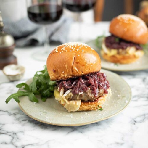 A brie burger in a bun with rocket and red wine caramelised onions