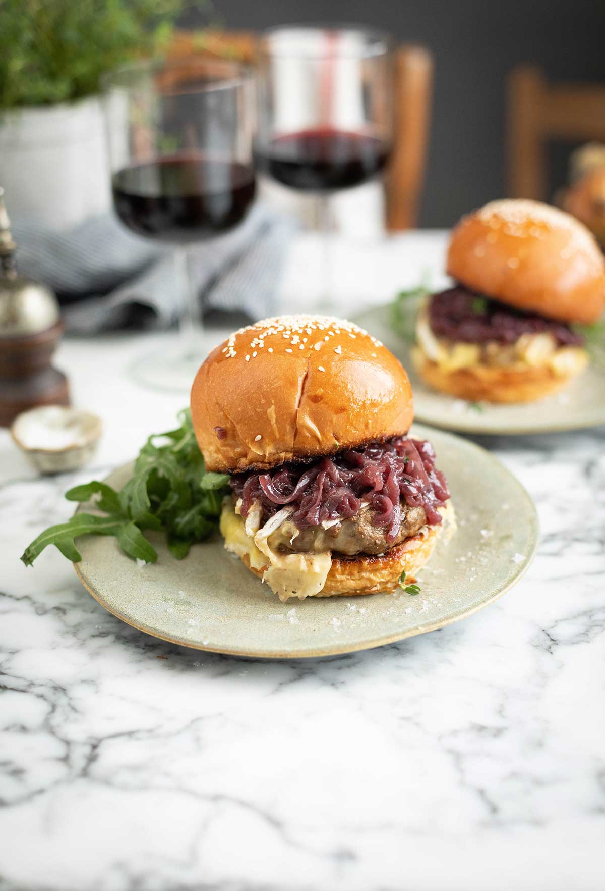 A brie burger in a bun with rocket and red wine caramelised onions