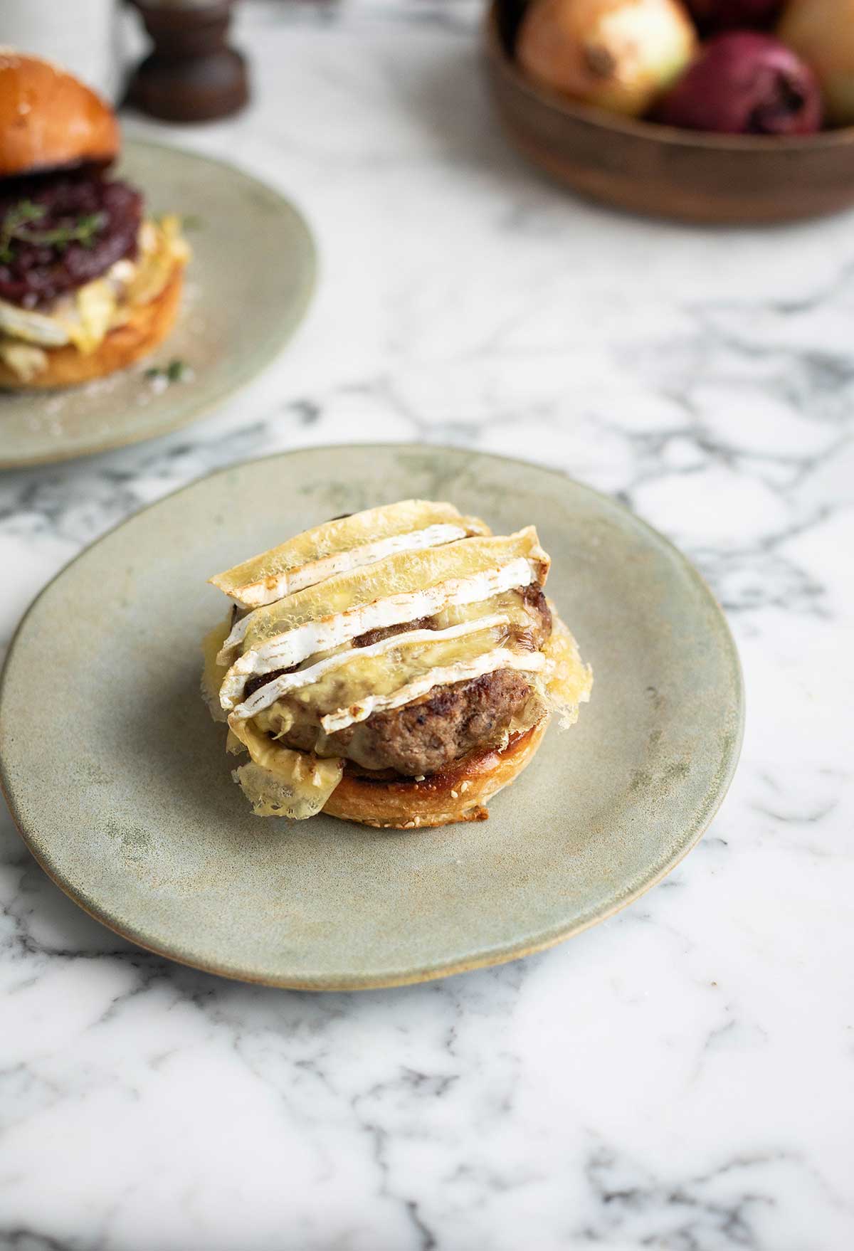 Melted Brie on a burger patty on a bun on a plate